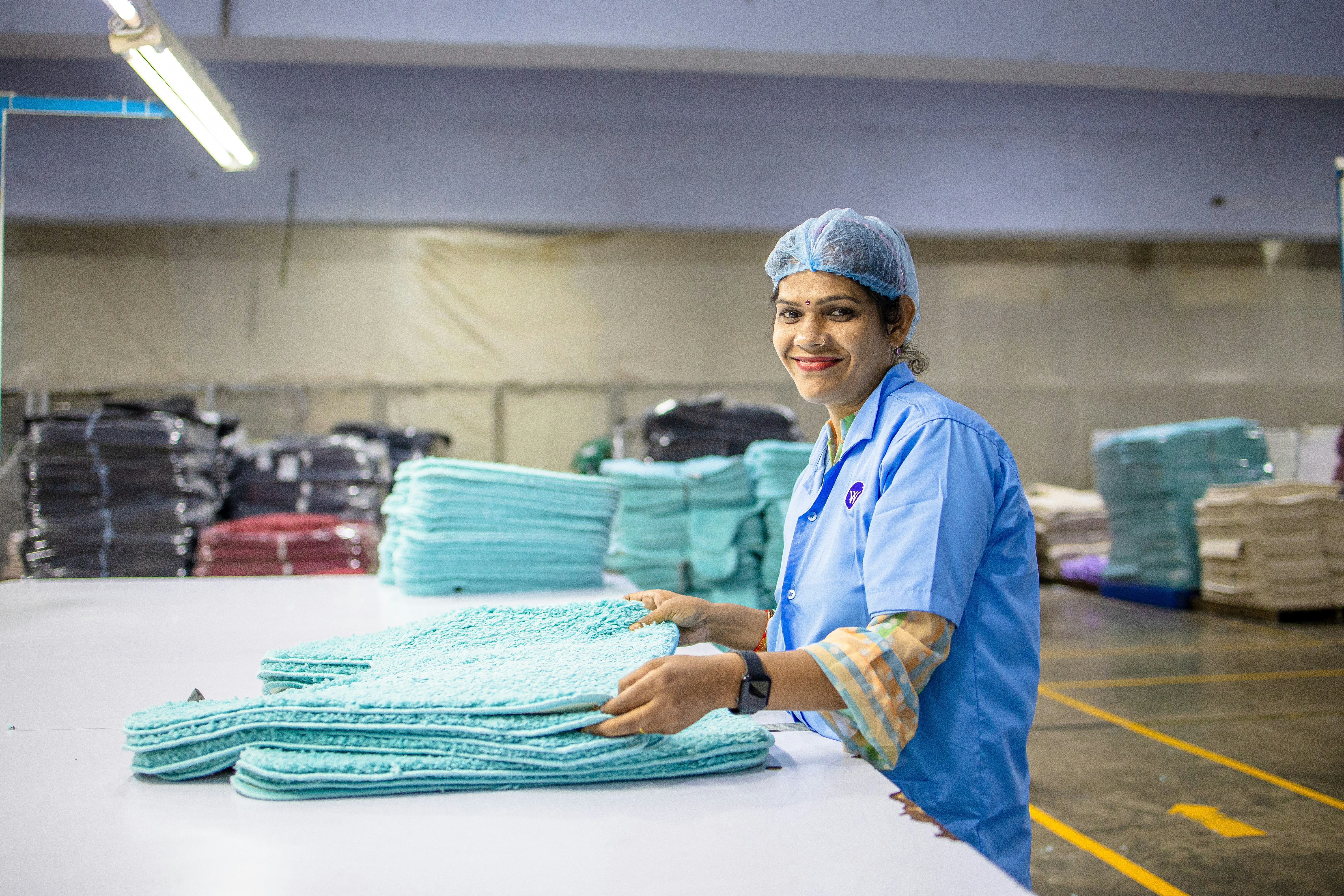 A woman folds textiles in a factory.