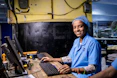 Woman in uniform smiles while using a computer.