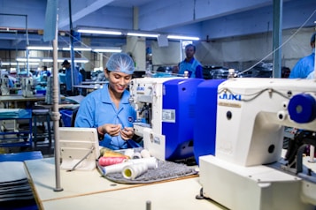 Woman sews at a garment factory with sewing machines.