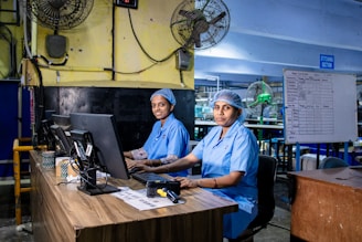 Factory workers in uniform are operating computers.