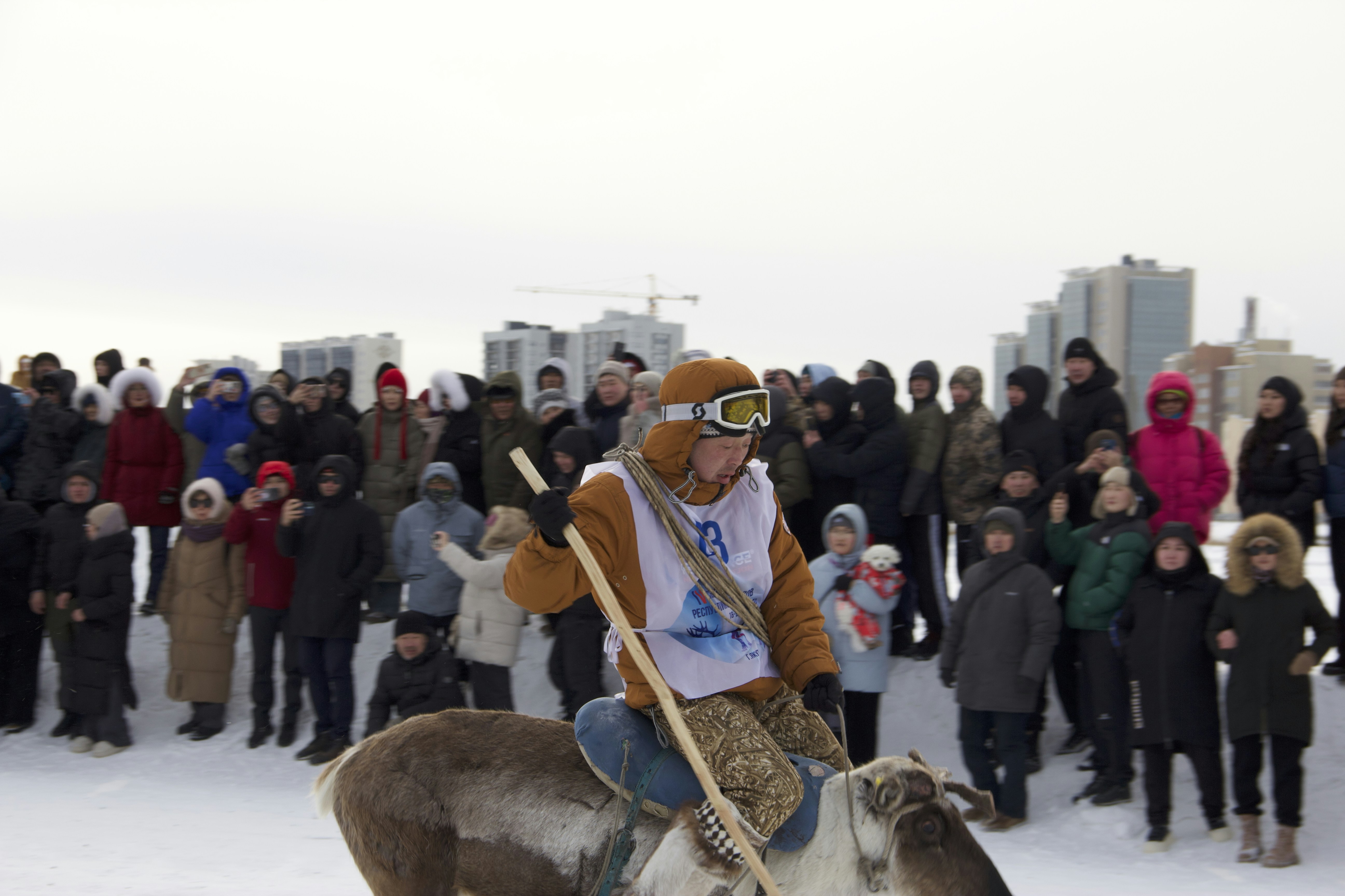 A person rides a reindeer in front of spectators.