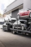 Cars on a carrier truck outside of a dealership.