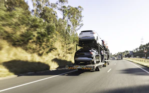 A car transporter truck drives along the highway.
