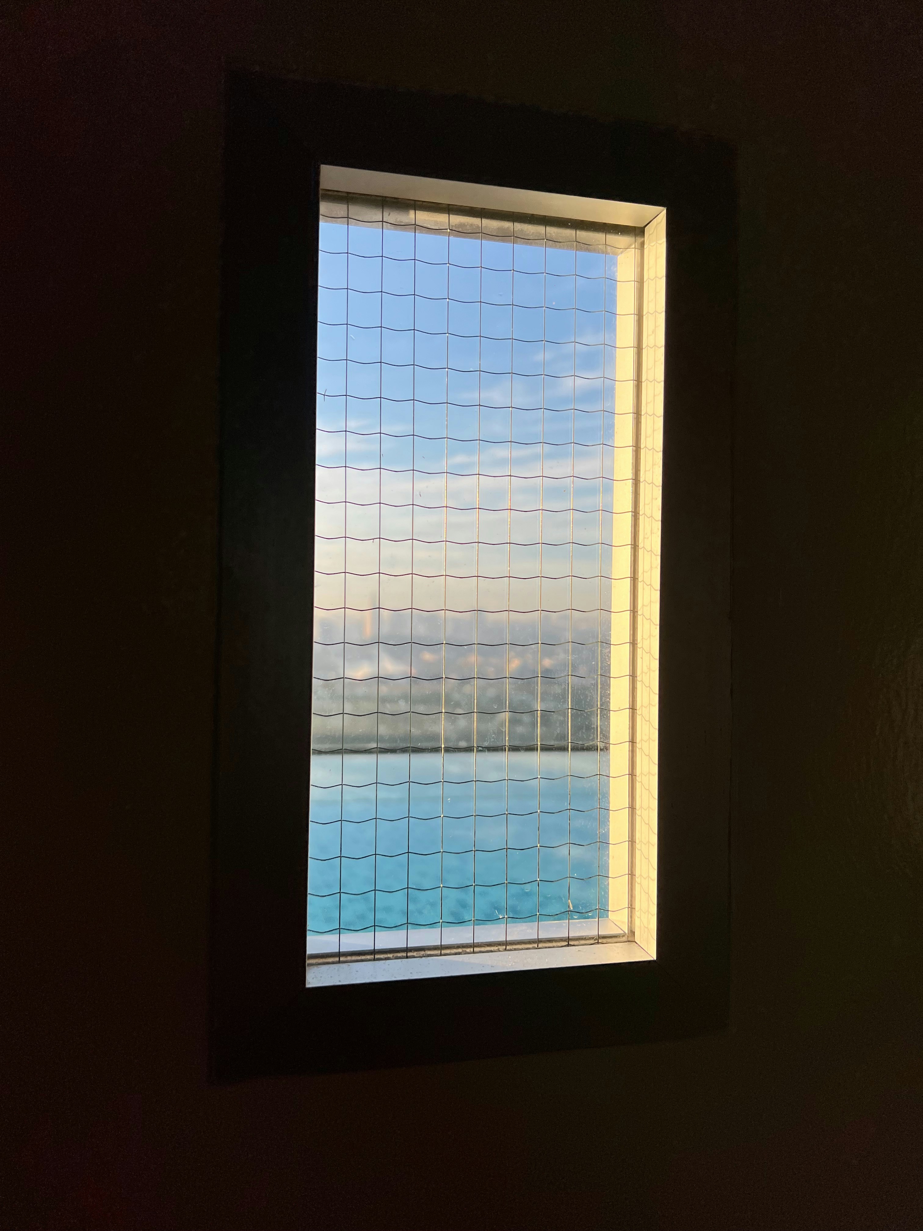 Una finestra offre una vista sull'acqua e sul cielo.