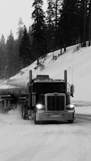 A tanker truck drives on a snowy road.
