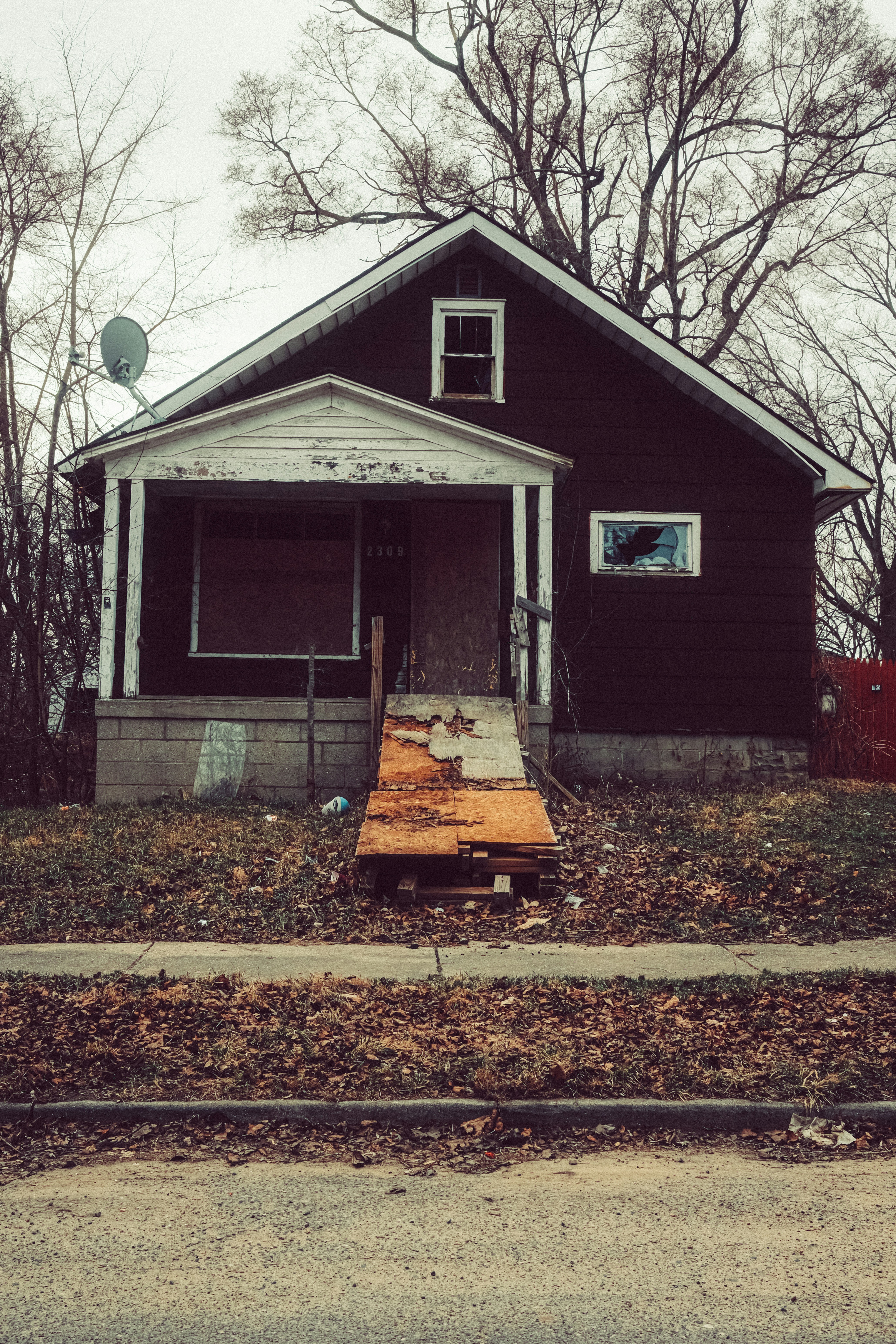 A dilapidated house stands among bare trees