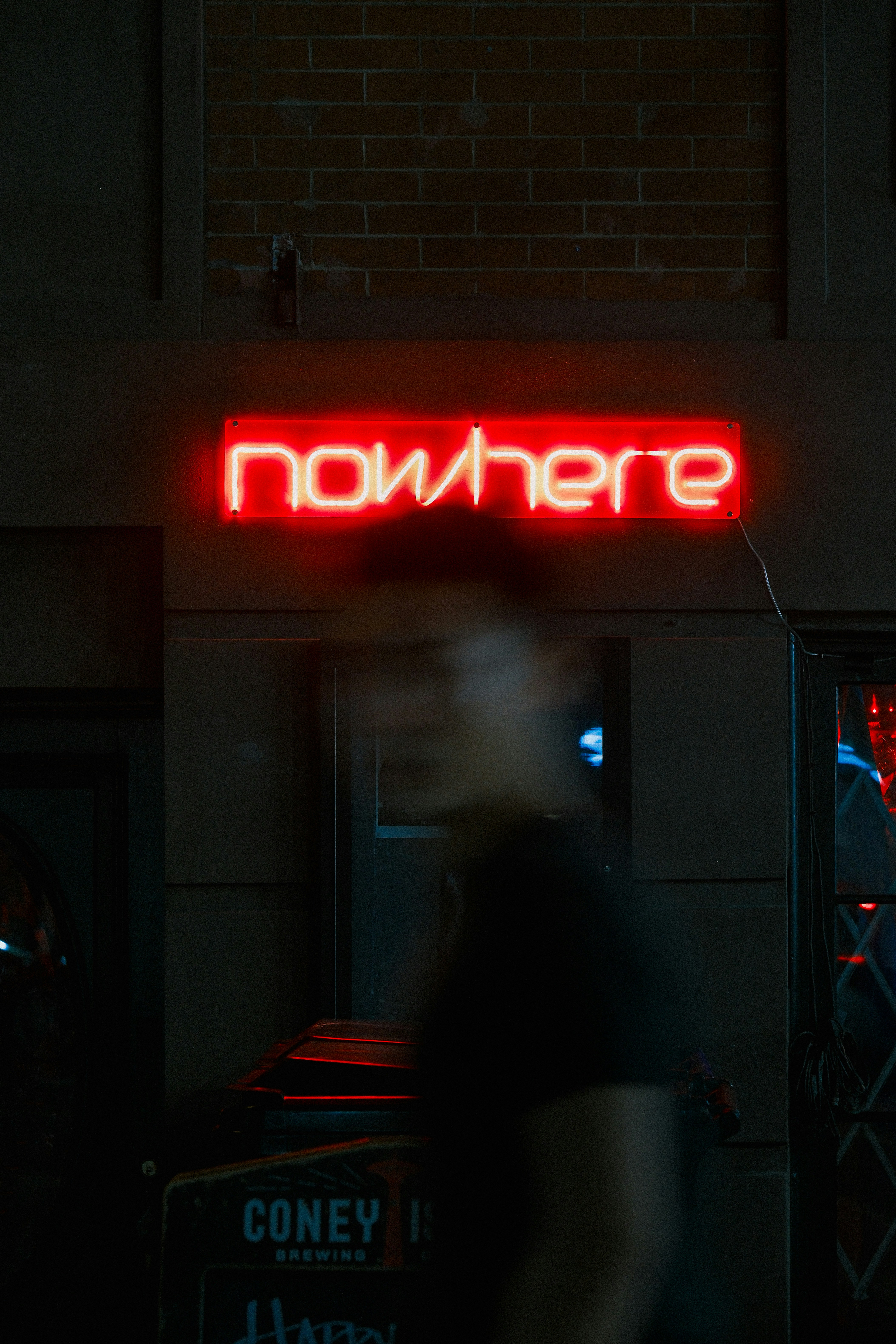 Enseigne lumineuse rouge « nulle part » avec une personne floue.