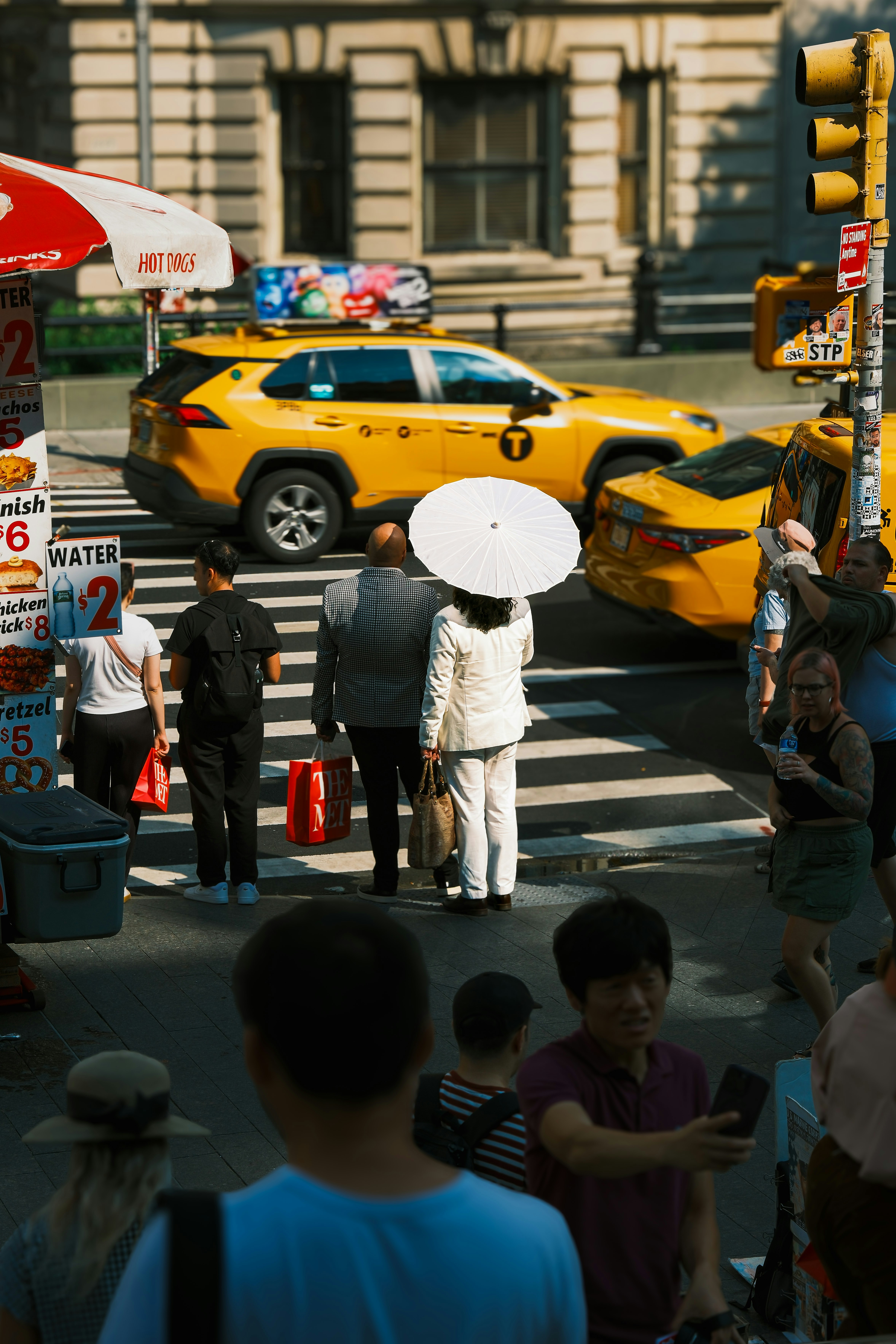 Des gens traversent une rue de New York près de taxis jaunes.