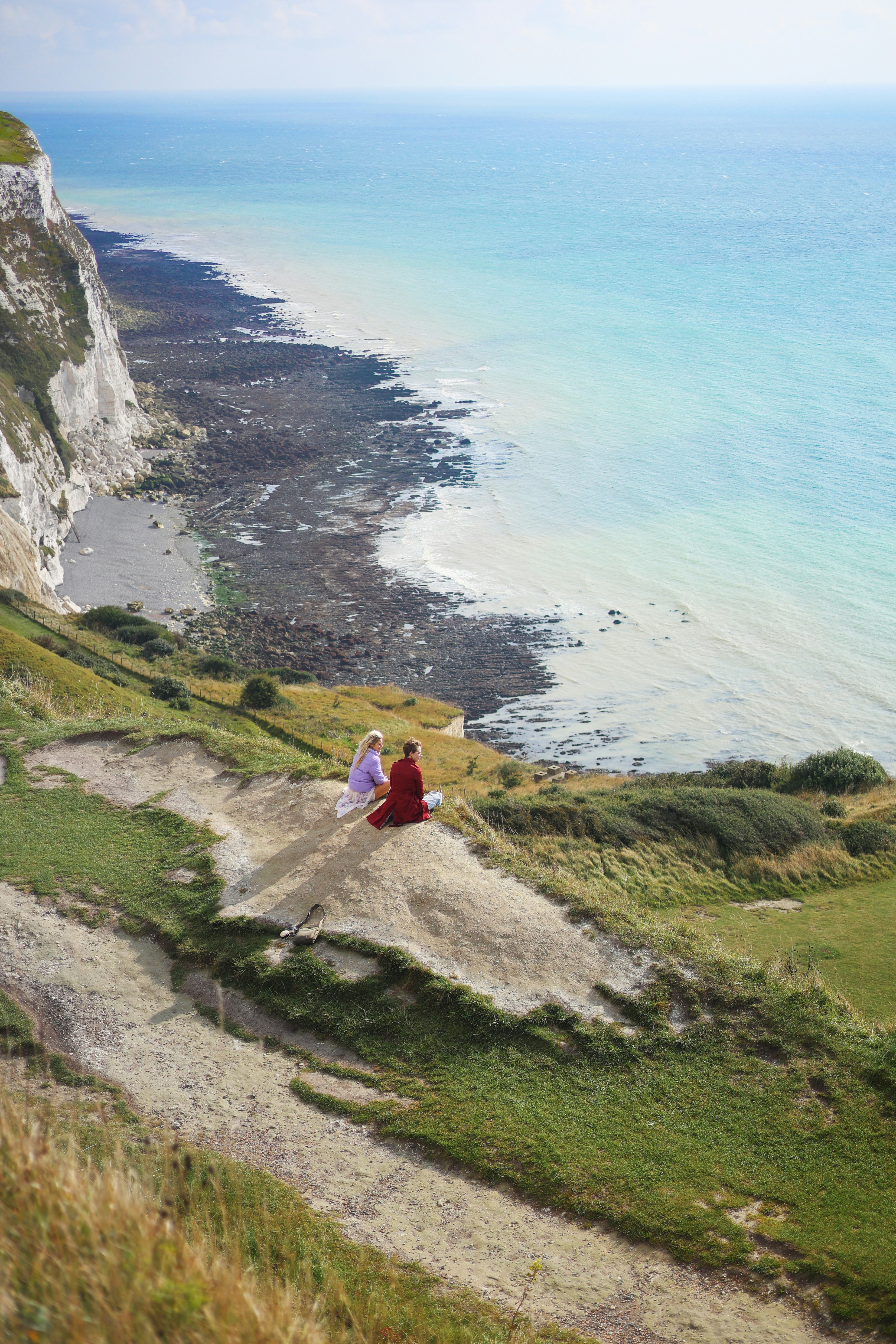 Die Menschen sitzen auf einem Hügel mit Blick auf das Meer.