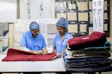 Two women are examining mats in a factory.