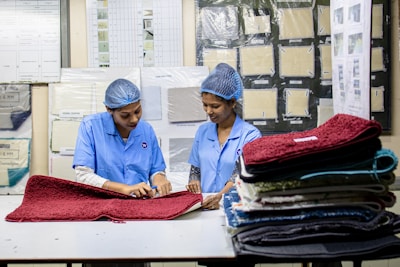 Two women are examining mats in a factory.