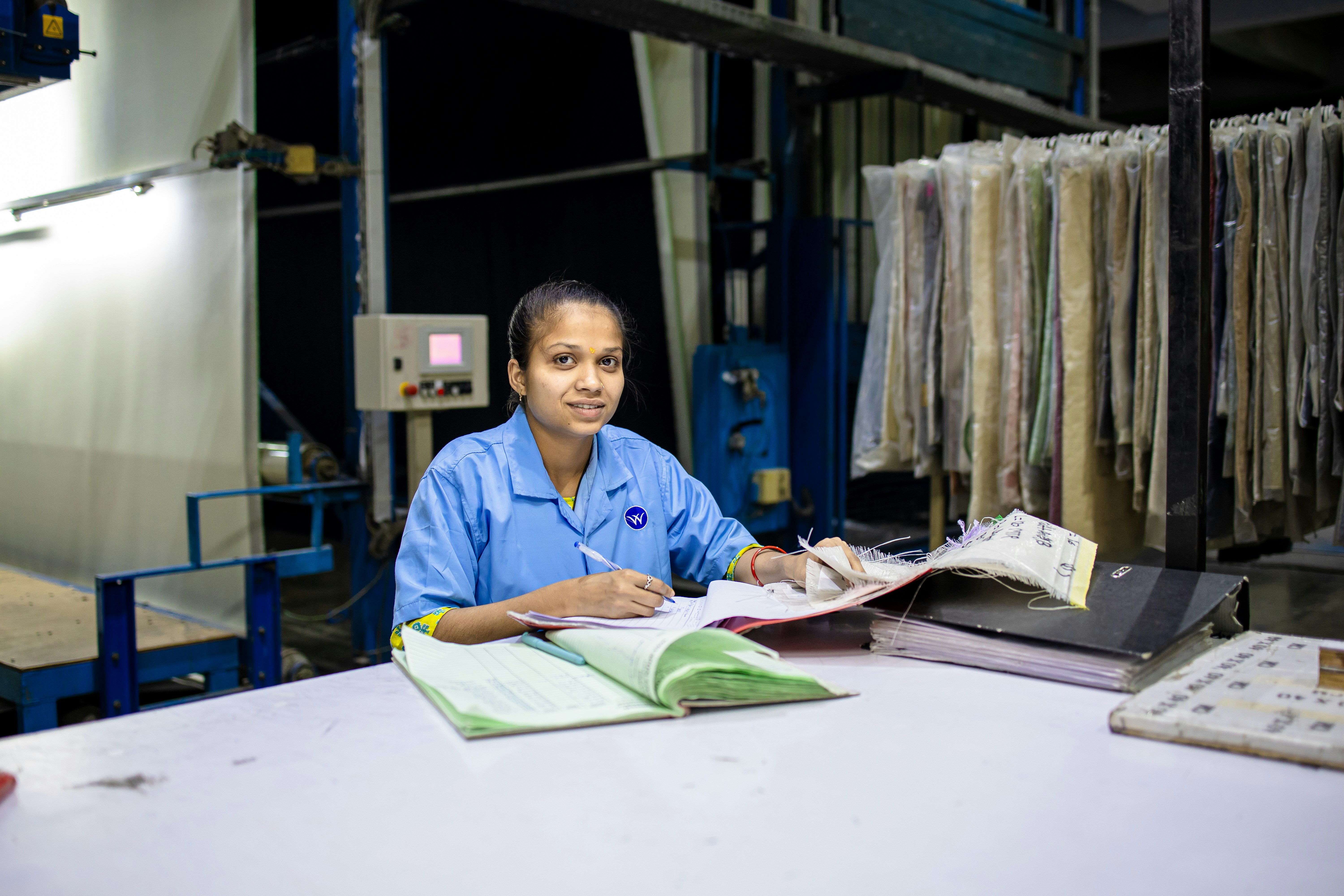 Woman working in a warehouse setting with a notebook.