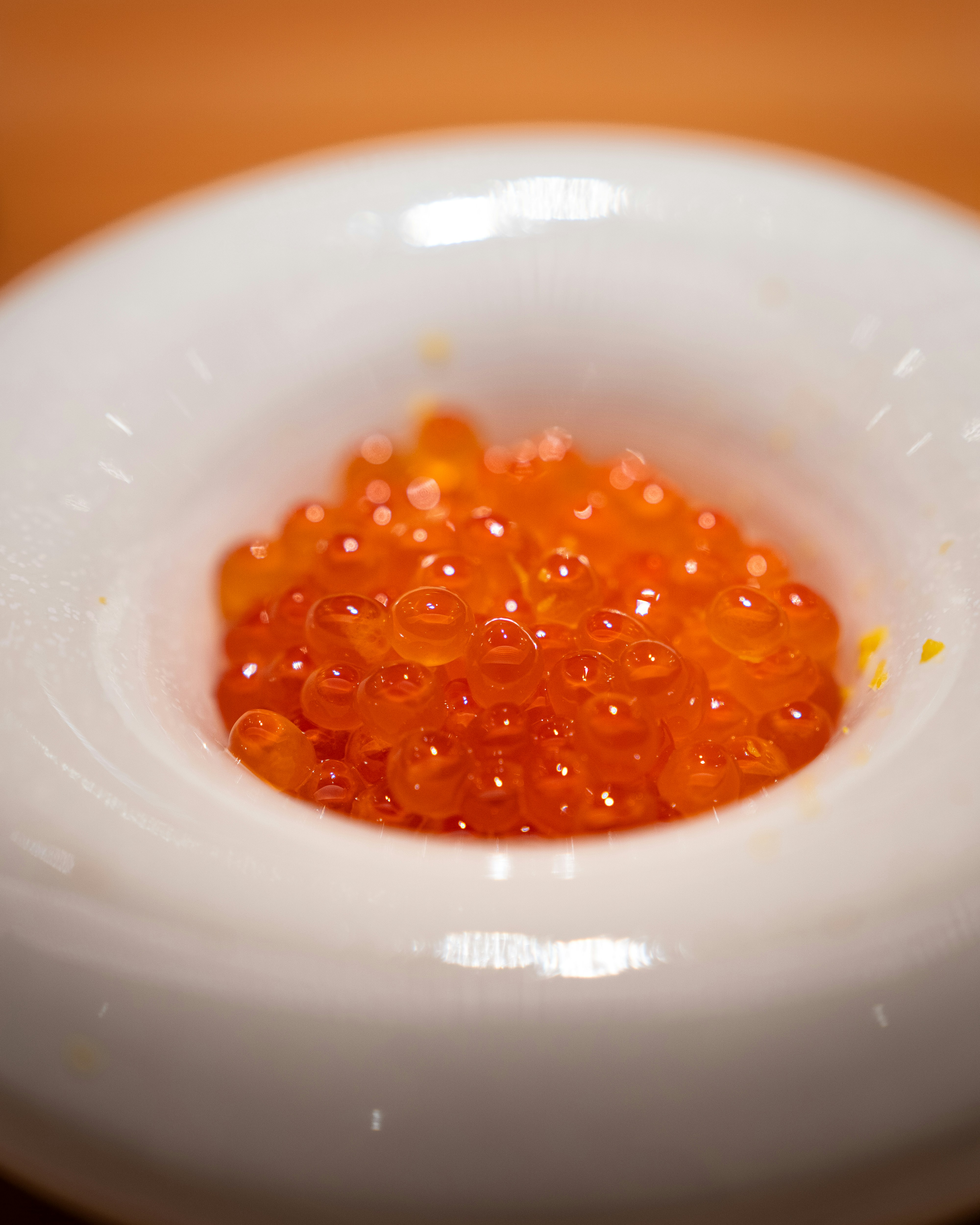 A bowl contains bright orange salmon roe.