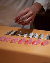 Sushi chef prepares fresh fish slices.