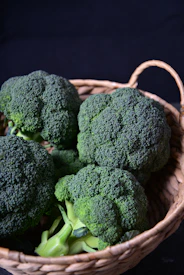 Fresh broccoli is in a woven basket.
