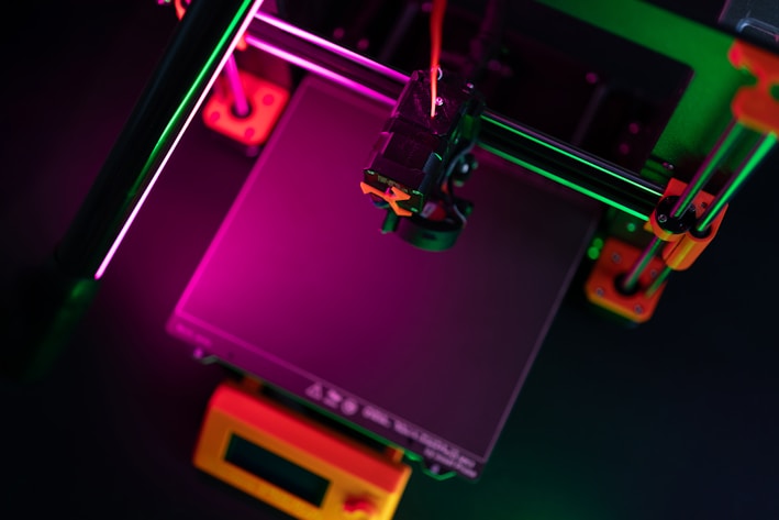 A 3D printer illuminated with colorful lights.