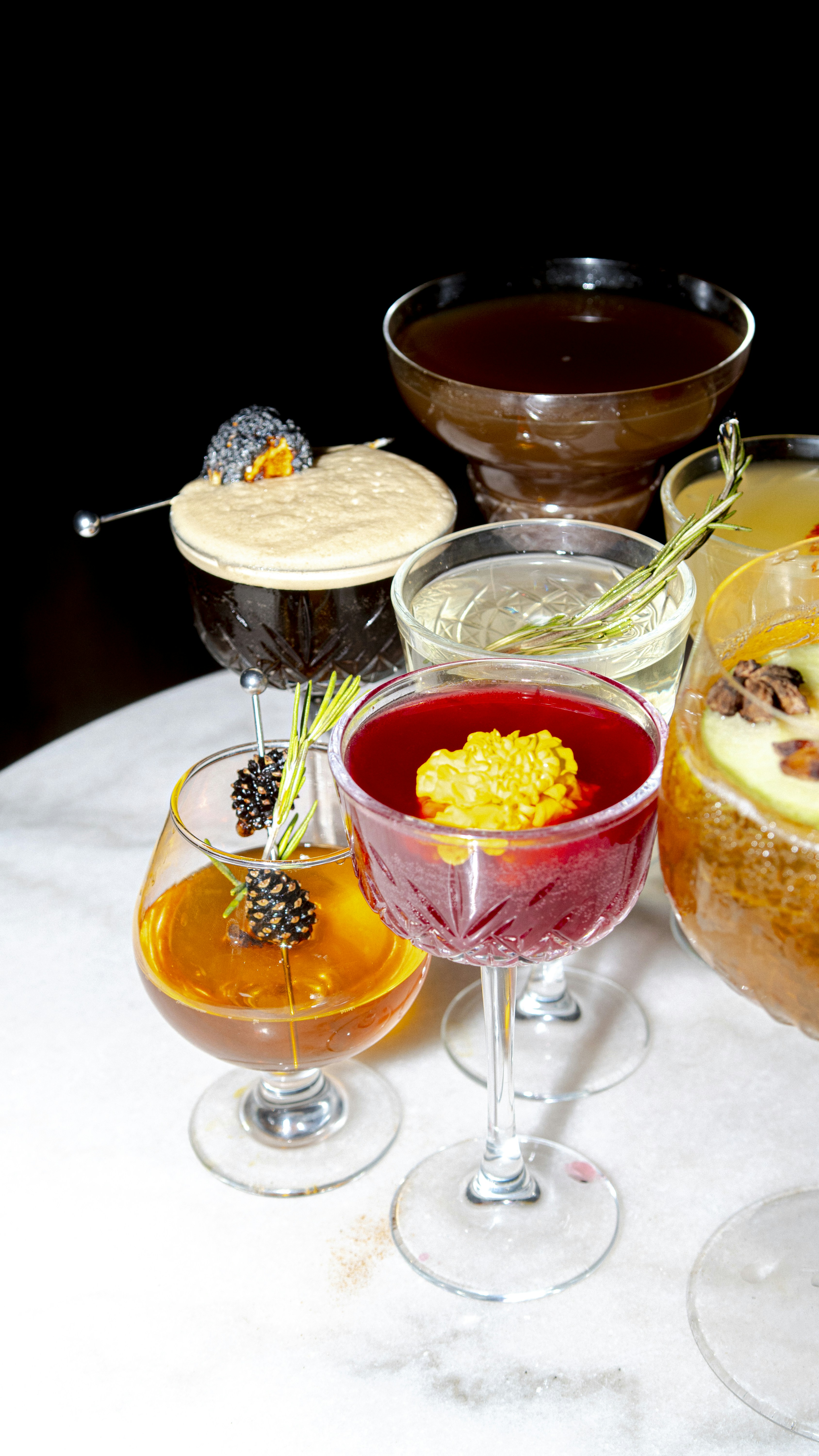 Several beautifully decorated cocktails are arranged on a surface.