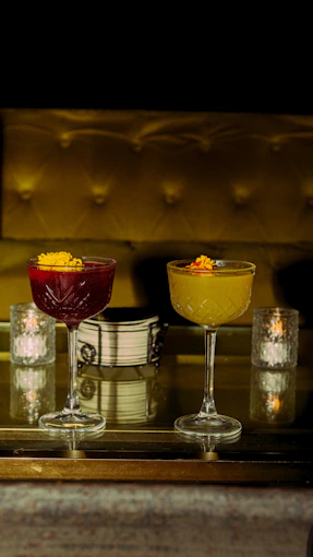 Two cocktails with floral garnishes are on display