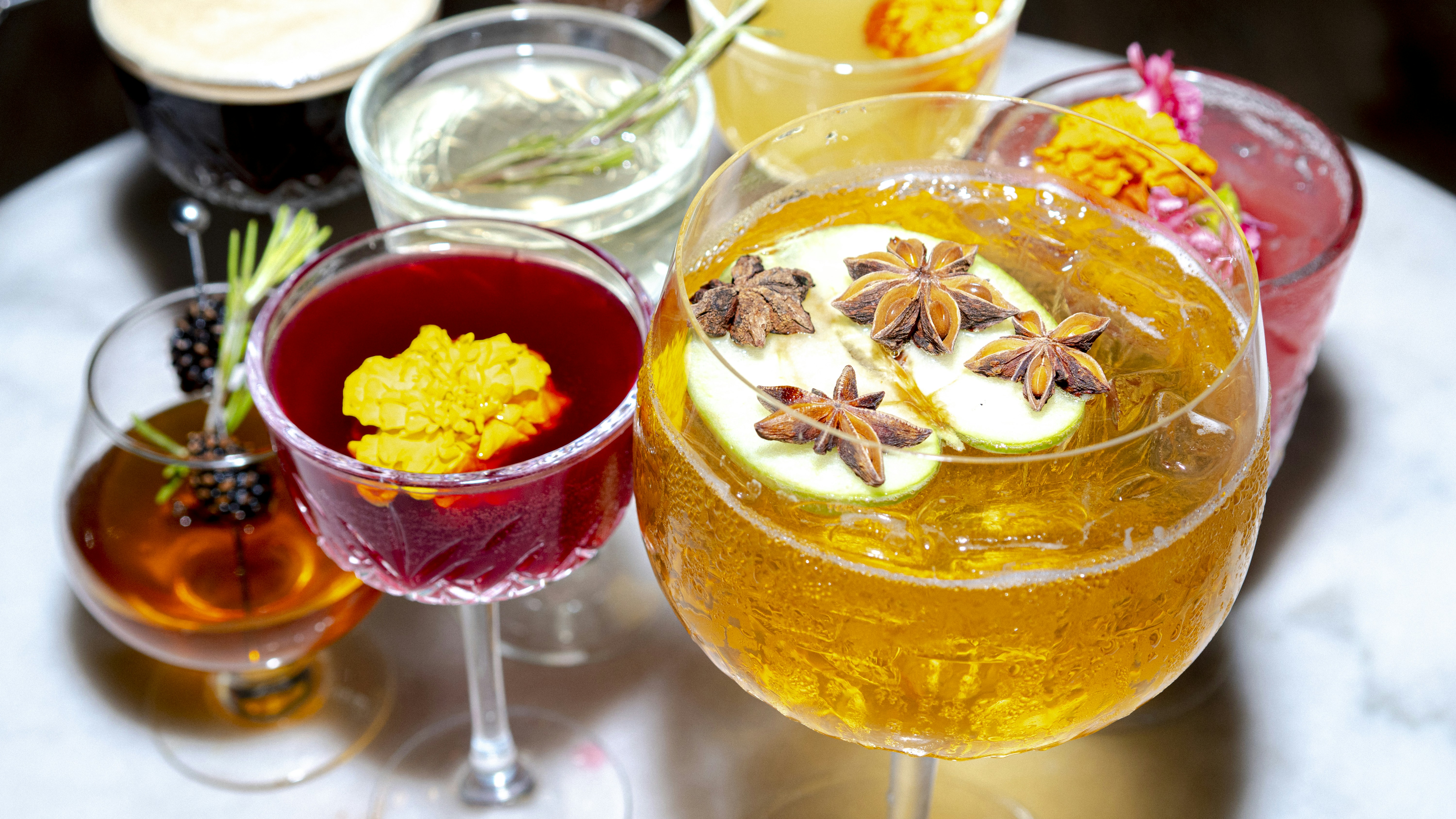 Colorful array of craft cocktails including purple chicha morada mimosas, green sake sangria, and garnished bloody marys - River North boozy brunch