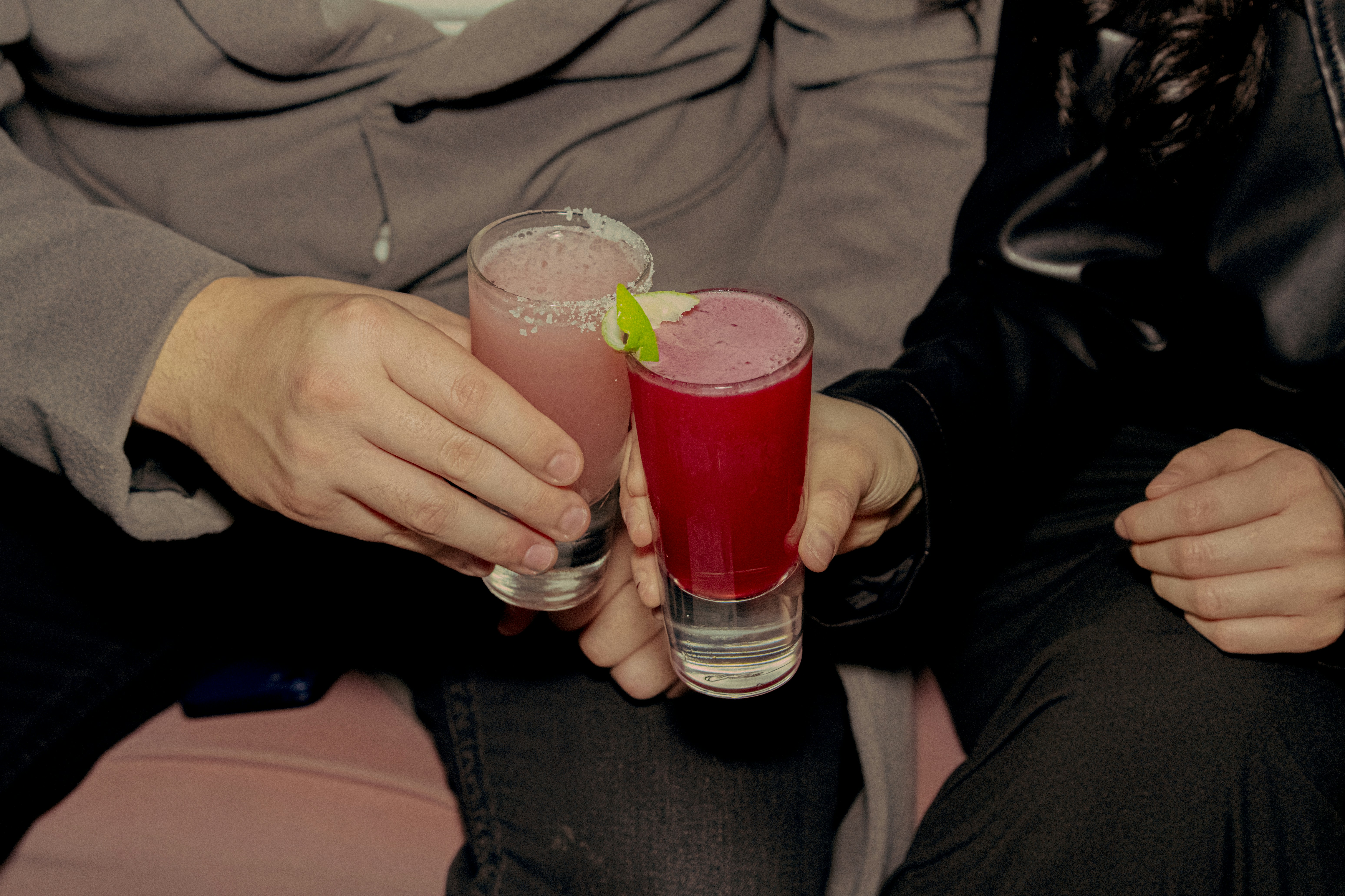 People clinking colourful cocktails