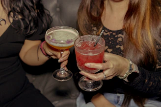 Two friends toast with cocktails in hand.