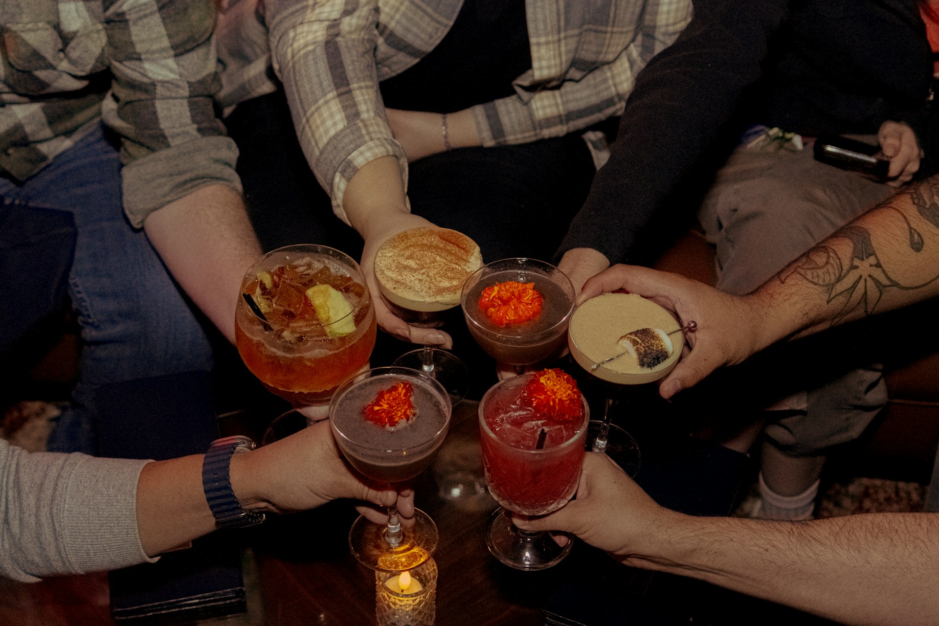 People clink cocktails together in a celebratory toast.