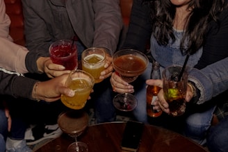 Friends toast with drinks in a bar setting.