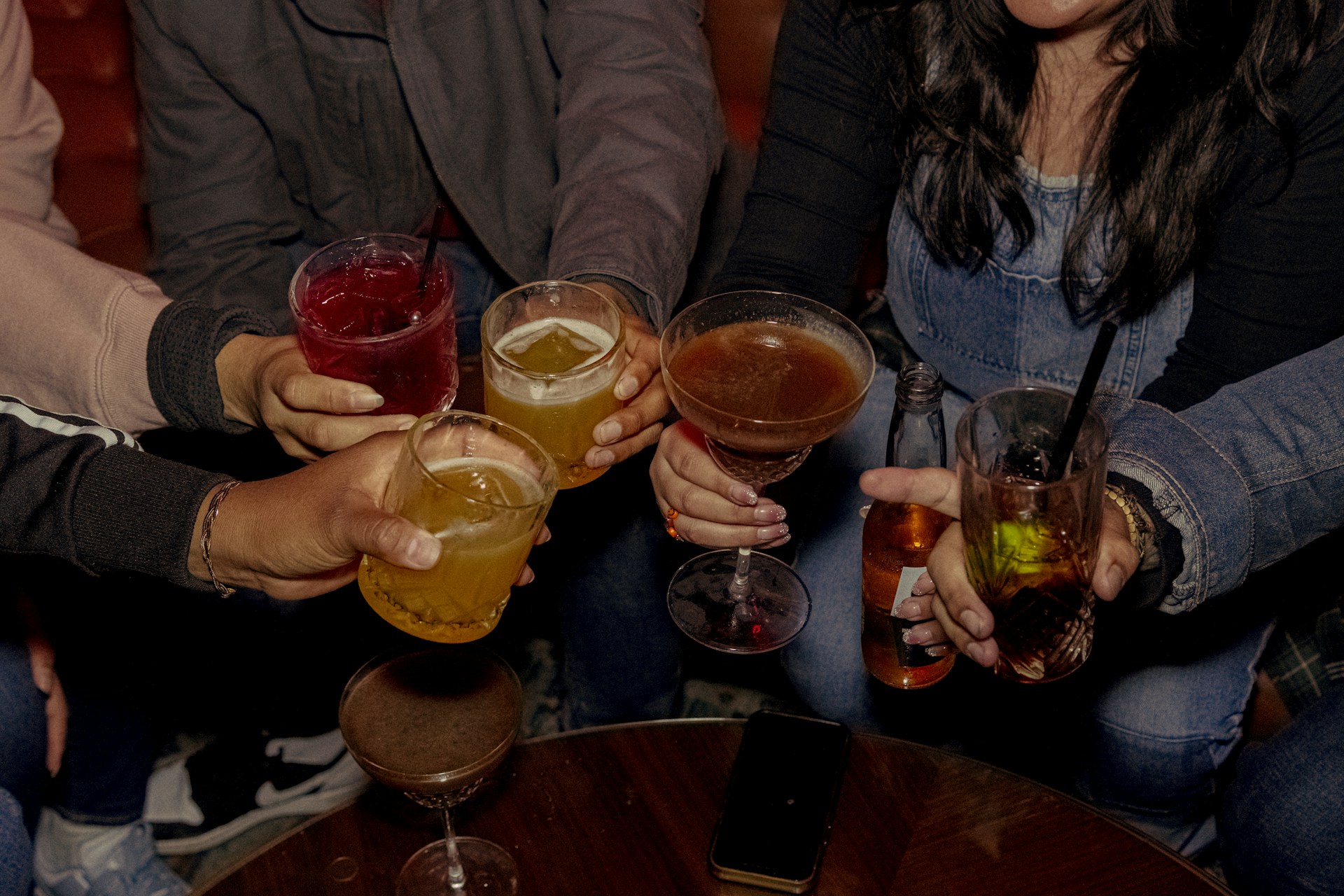 Friends toast with drinks in a bar setting.