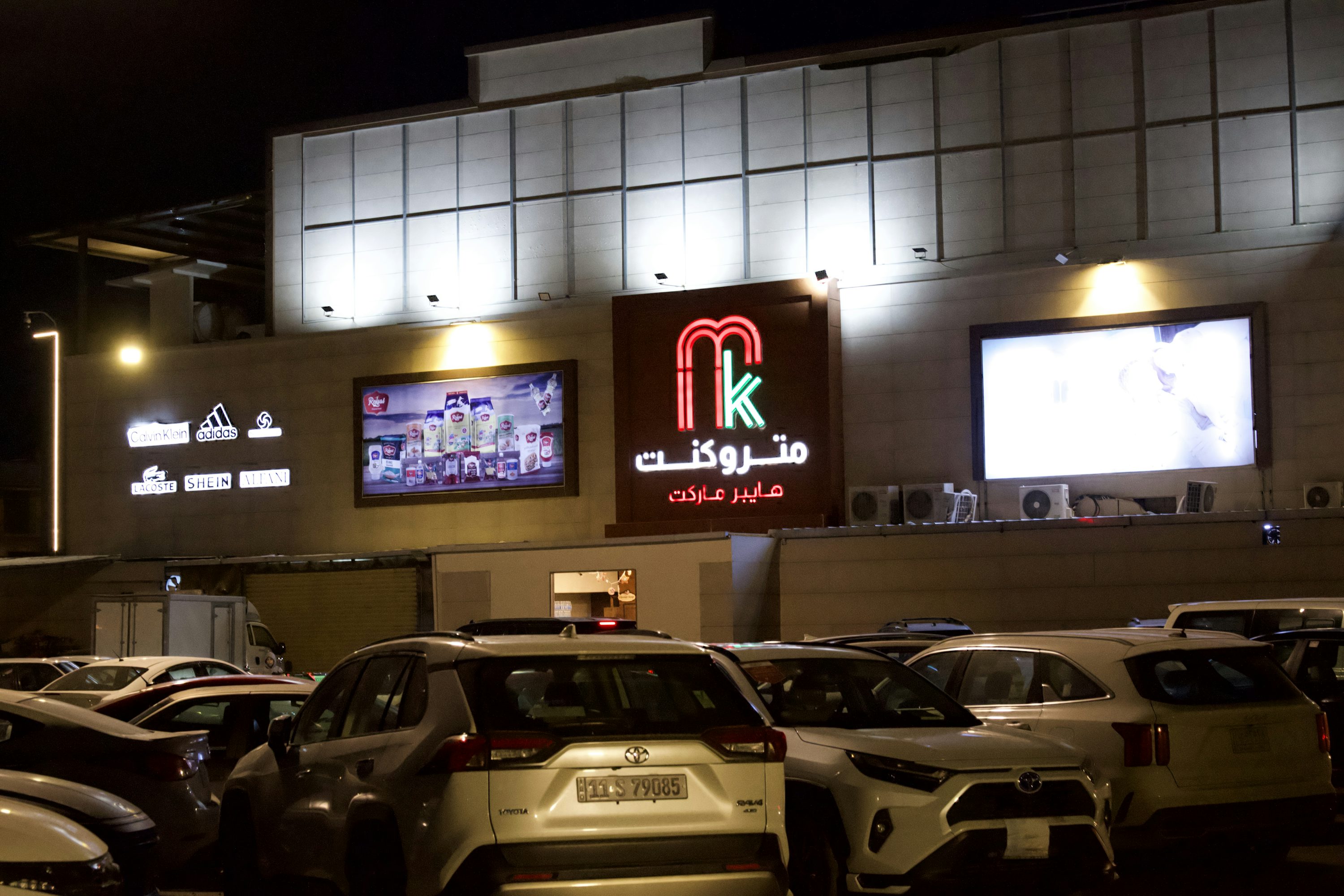 A shopping center at night with lit signs.