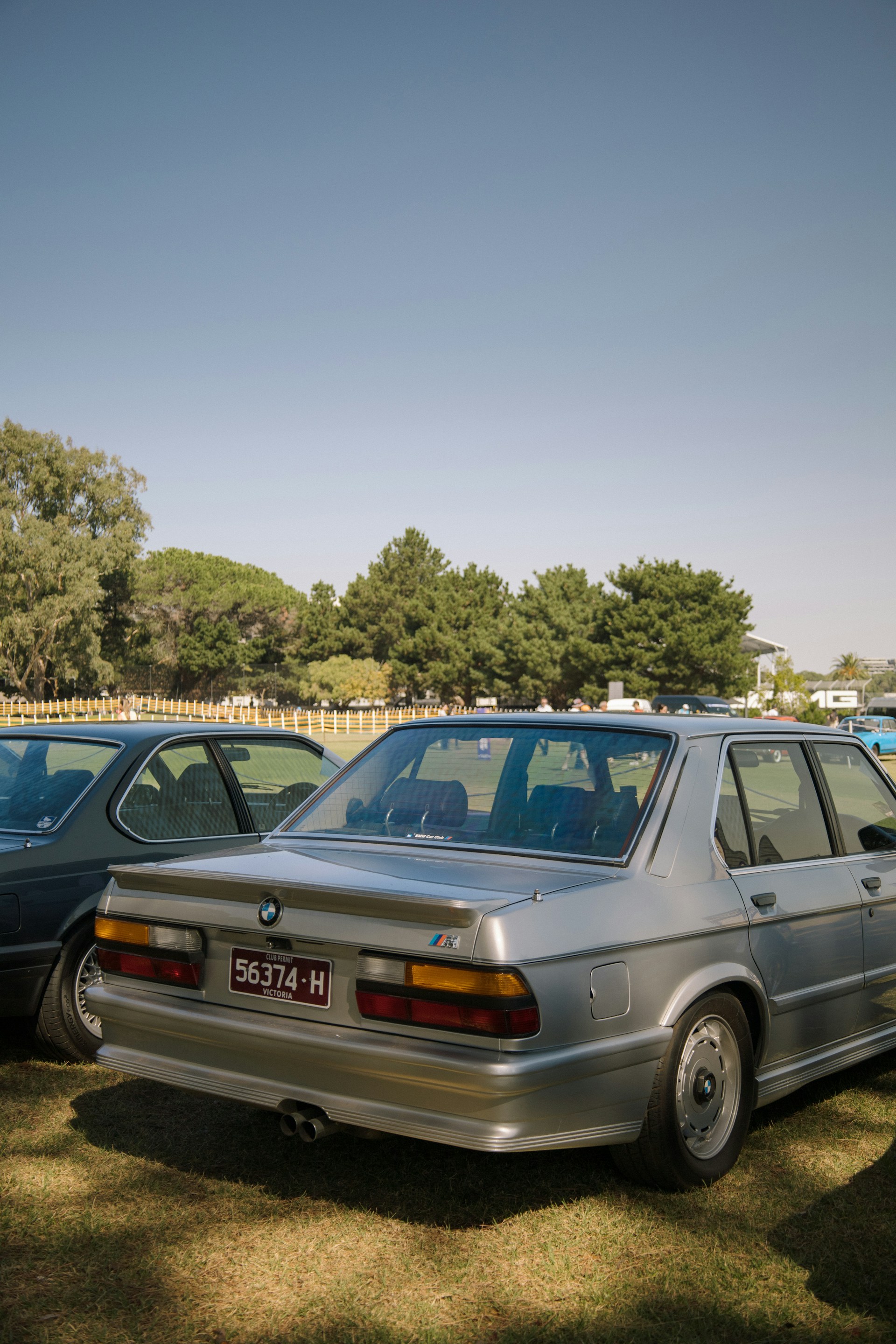 A vintage BMW sedan is parked outdoors on grass.