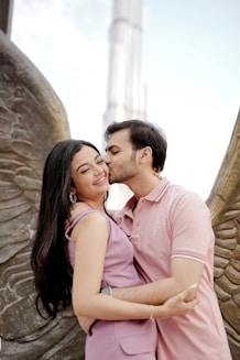 A couple enjoys a sweet kiss near angel wings.