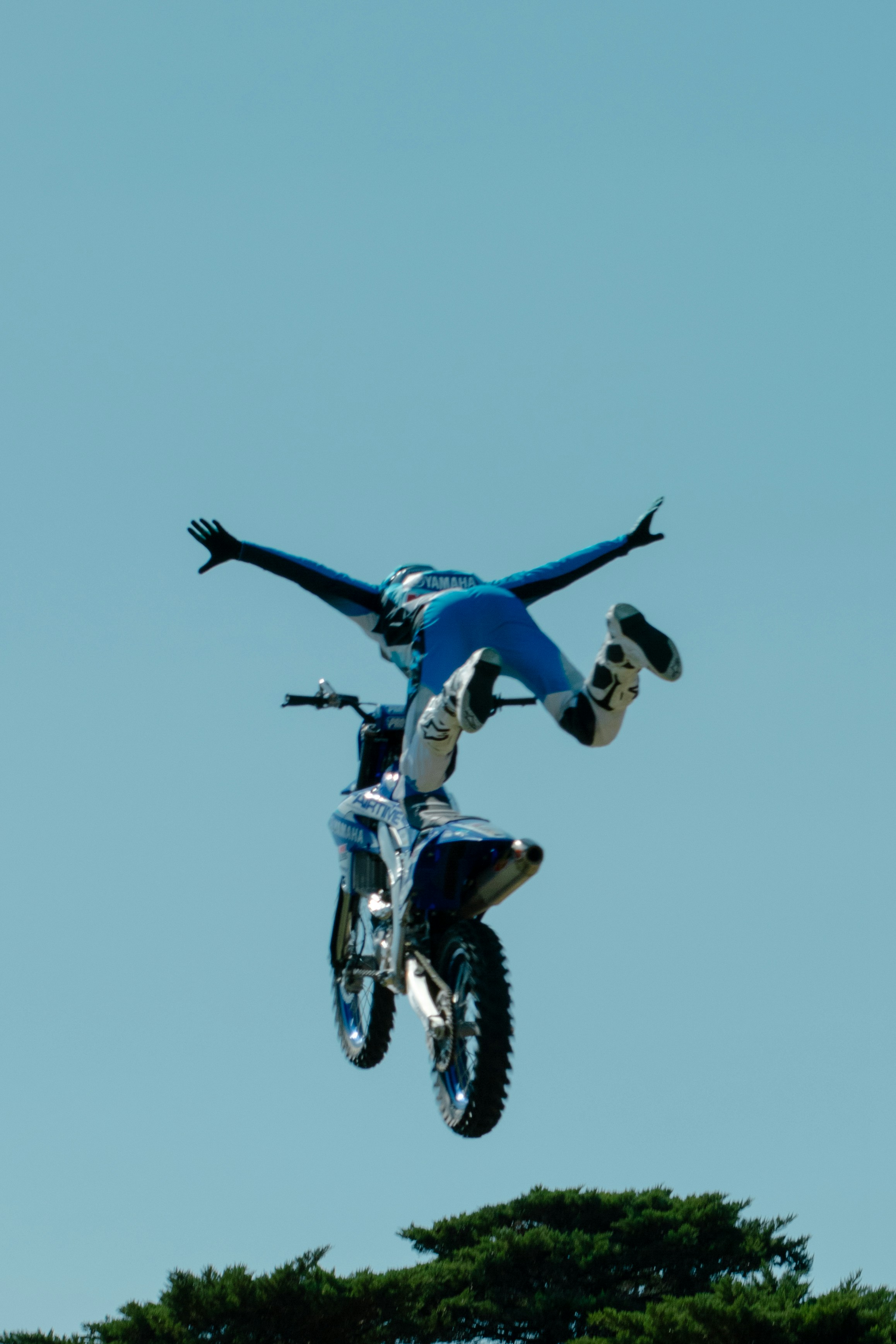 Der Motorradfahrer führt mit ausgestreckten Armen einen Stunt in der Luft aus.