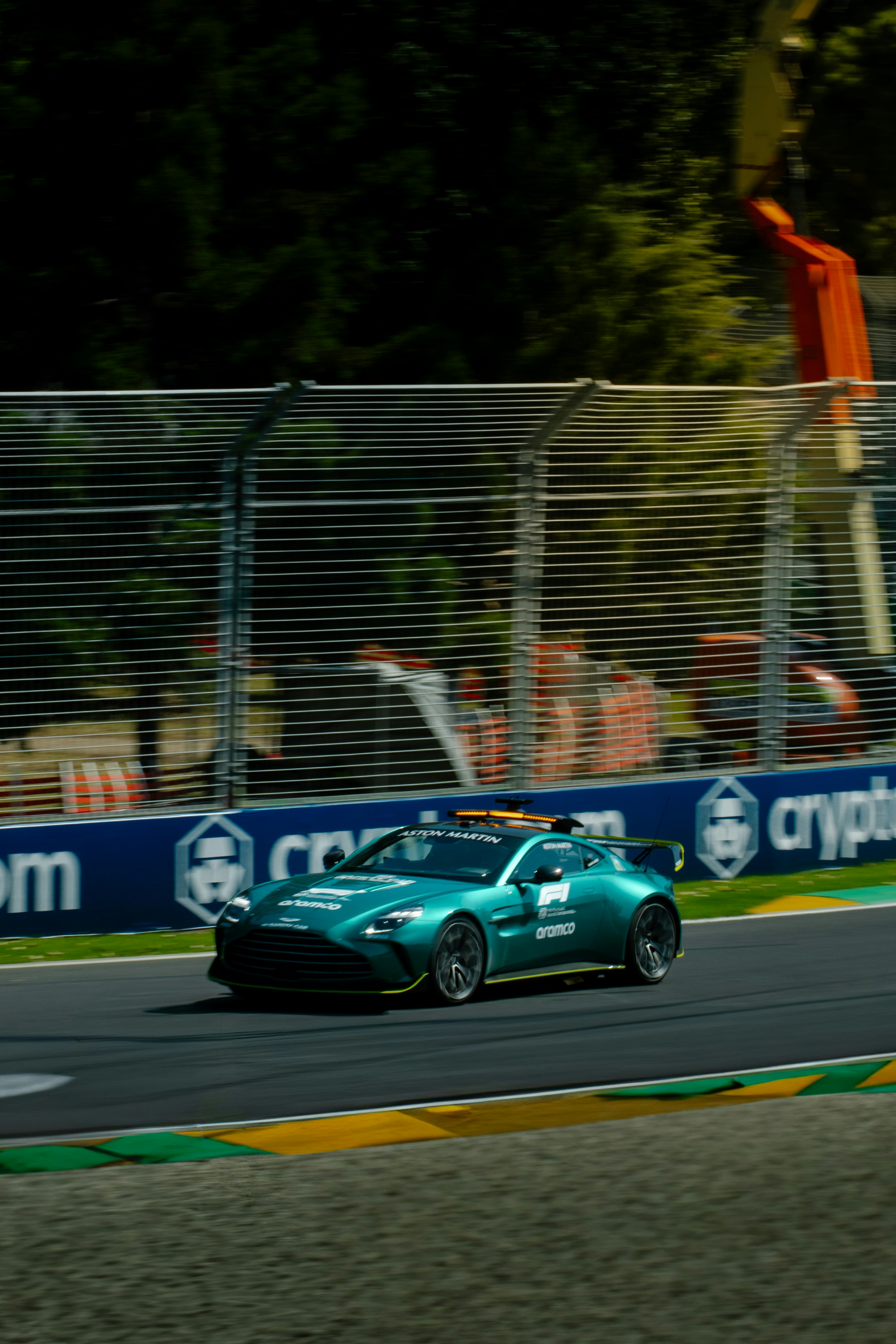 A green aston martin race car speeds along the track.