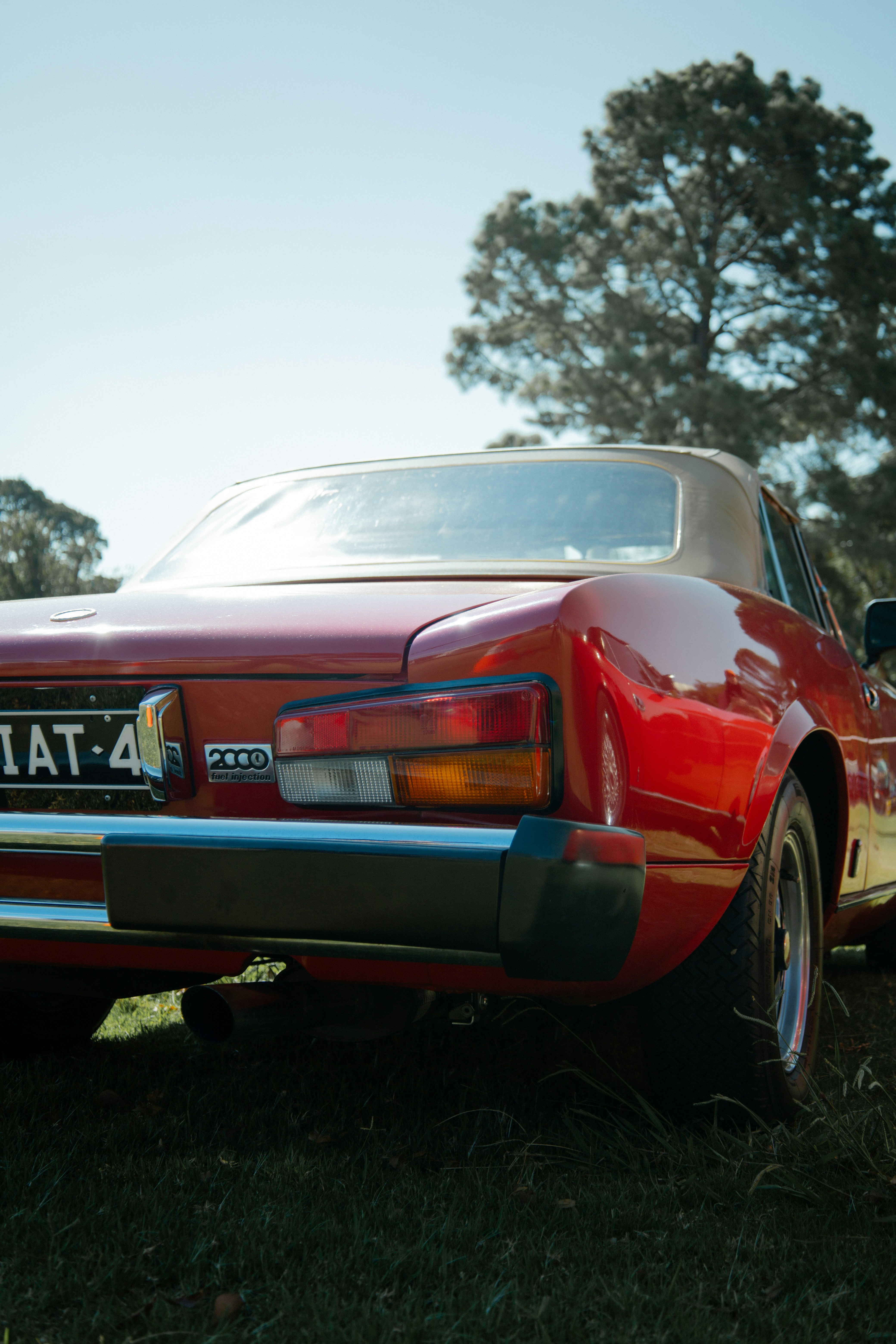 A classic red car is shown in the sunlight.