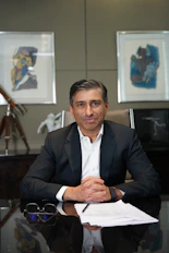 A man in a suit sits at a desk.
