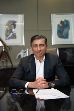 A man in a suit sits at a desk.