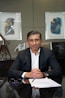 A man in a suit sits at a desk.