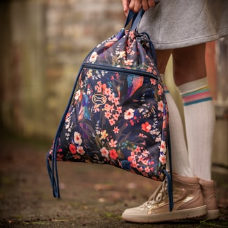 A girl holds a floral drawstring backpack.
