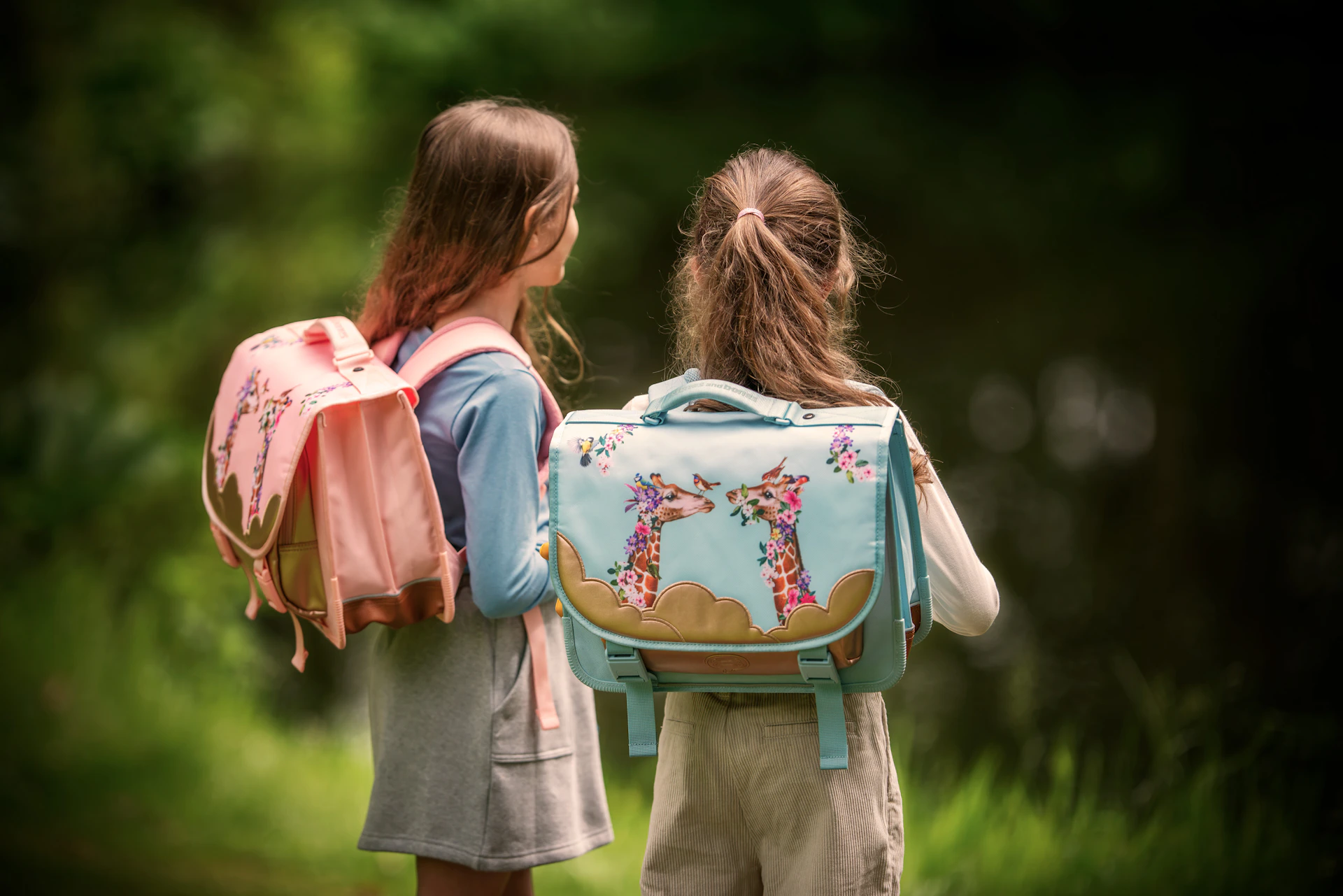 Two girls stand with their backpacks near water.