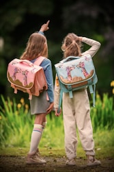 Two children with backpacks are gazing at something.