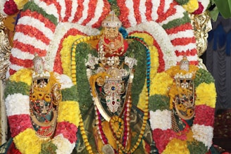 A decorated hindu idol adorned with garland flowers.