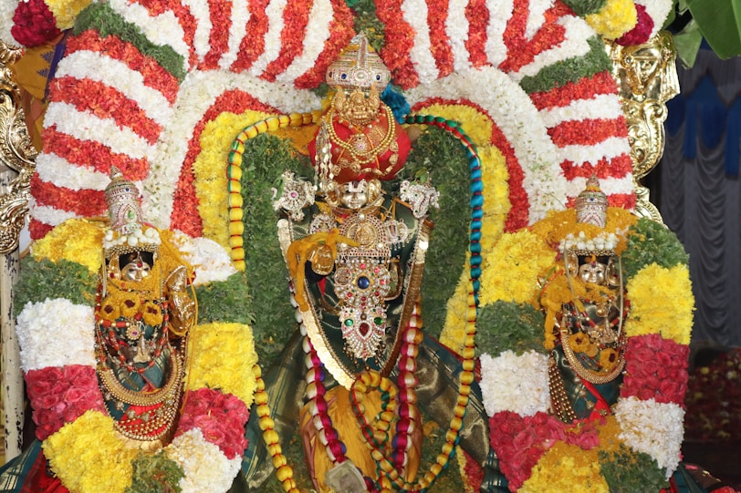 A decorated hindu idol adorned with garland flowers.