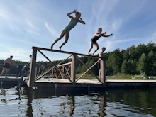 People are jumping off a dock into the water.