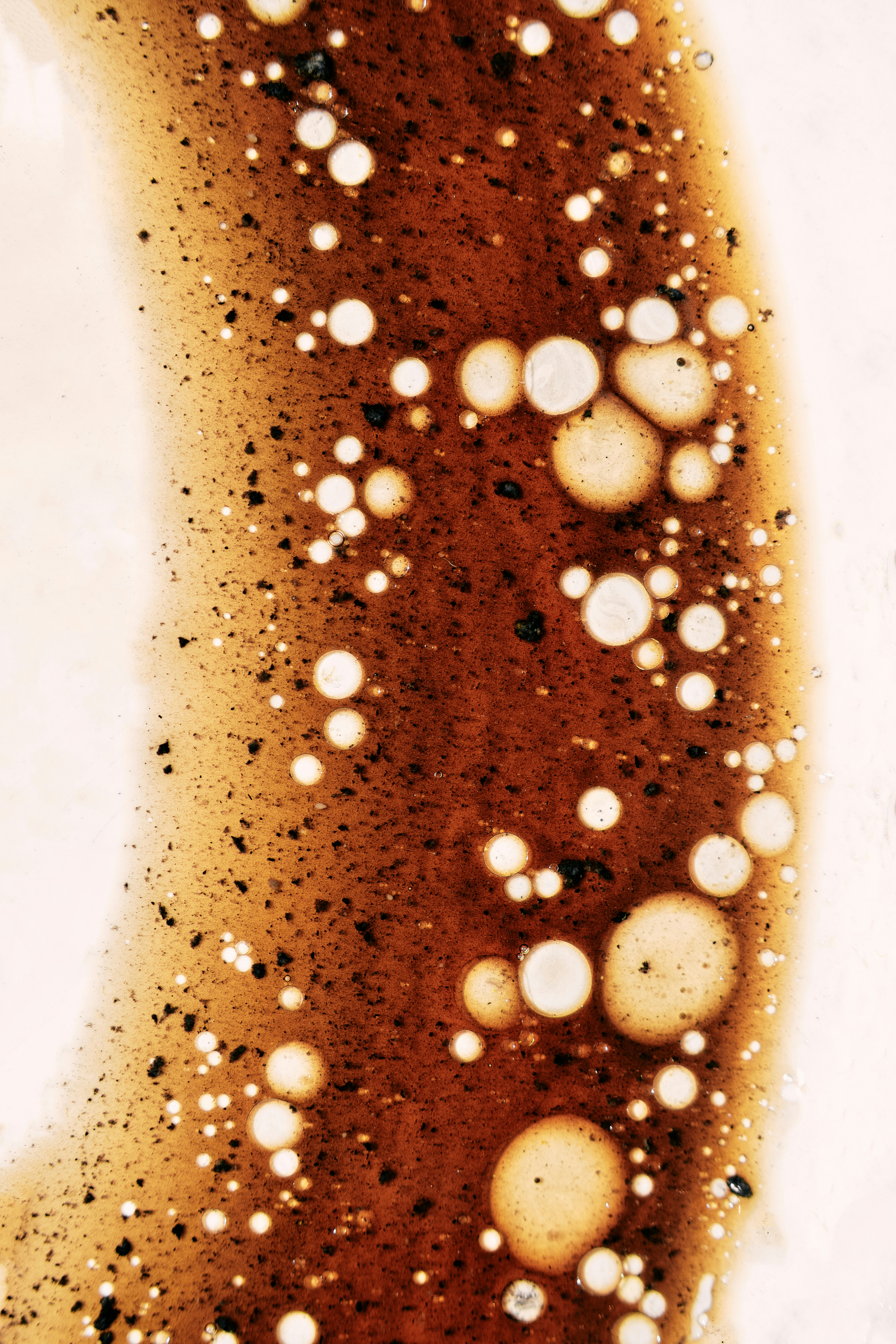 Braune Flüssigkeit mit weißen Blasen und Flecken.