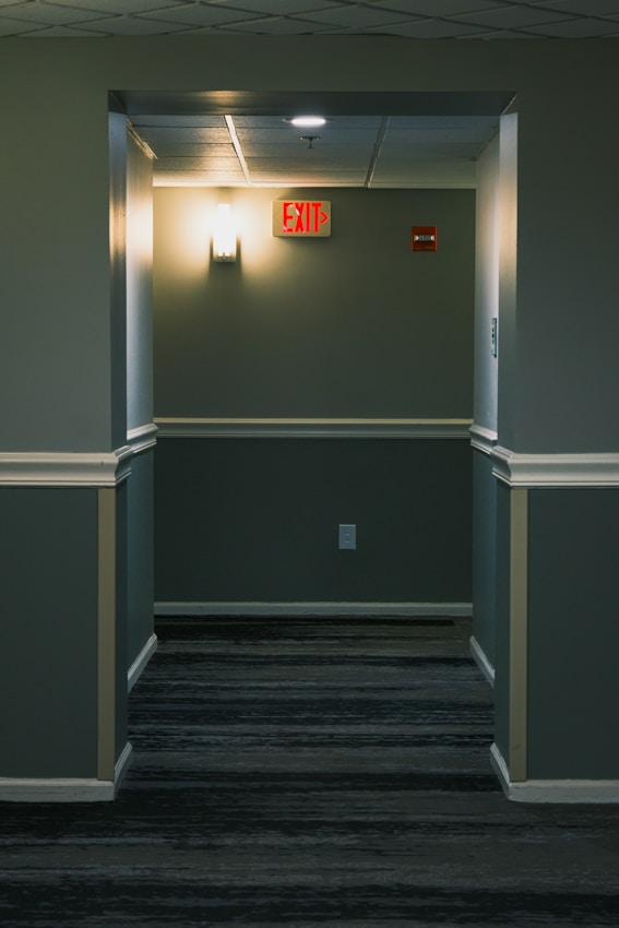 A hallway with an exit sign is visible.