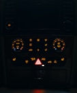 Dashboard controls of a vehicle illuminated at night.