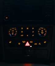 Dashboard controls of a vehicle illuminated at night.