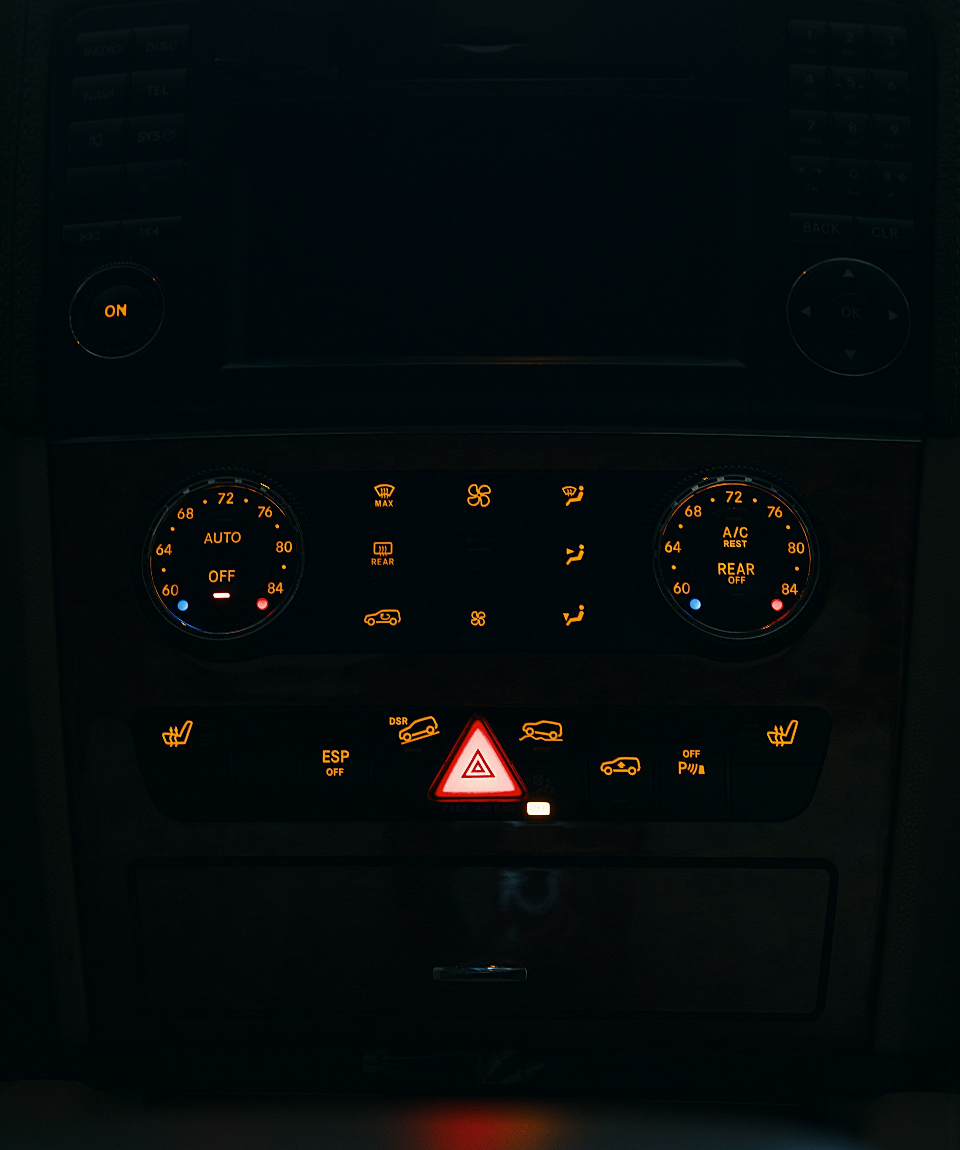 Dashboard controls of a vehicle illuminated at night.