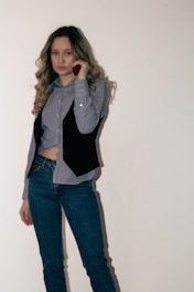 Woman in jeans and vest talks on the phone.
