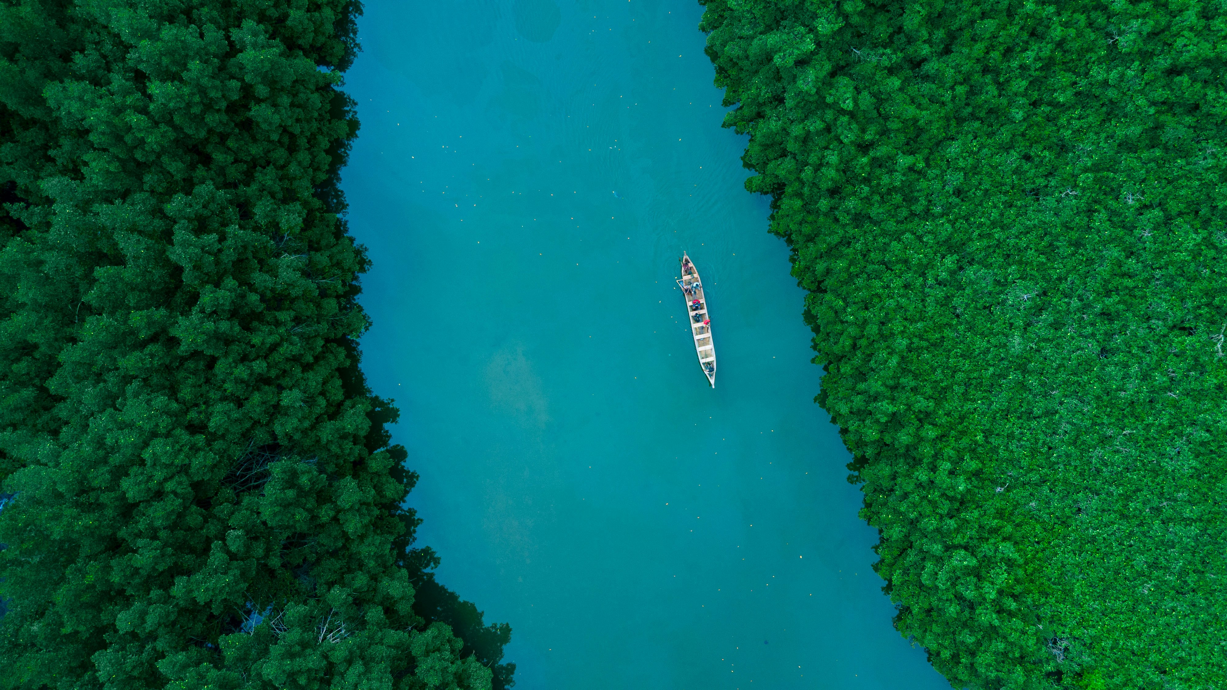 A boat sails down a turquoise river.